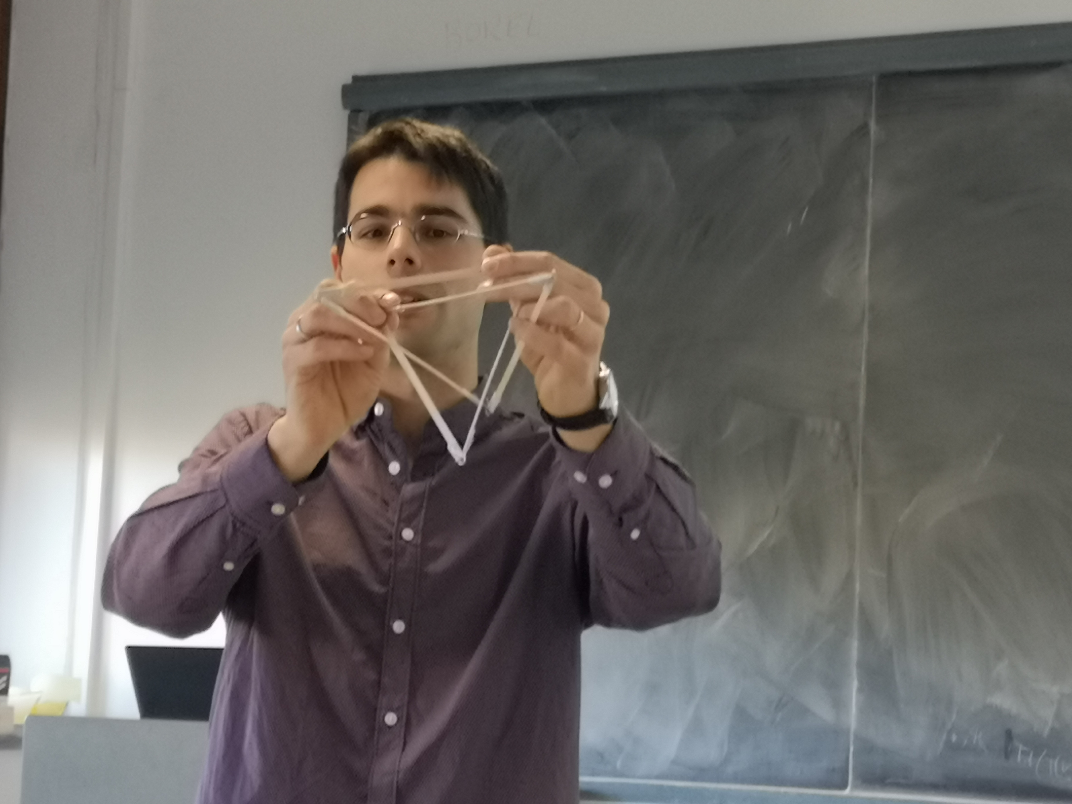 Math&eacute;maticien expliquant un concept math&eacute;matique avec un mod&egrave;le en bois