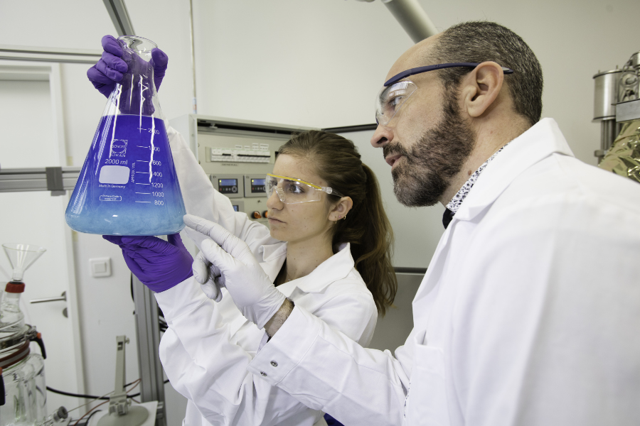 Deux chimistes, une femme et un homme, observant une r&eacute;action chimique dans une fiole appel&eacute;e erlenmeyer
