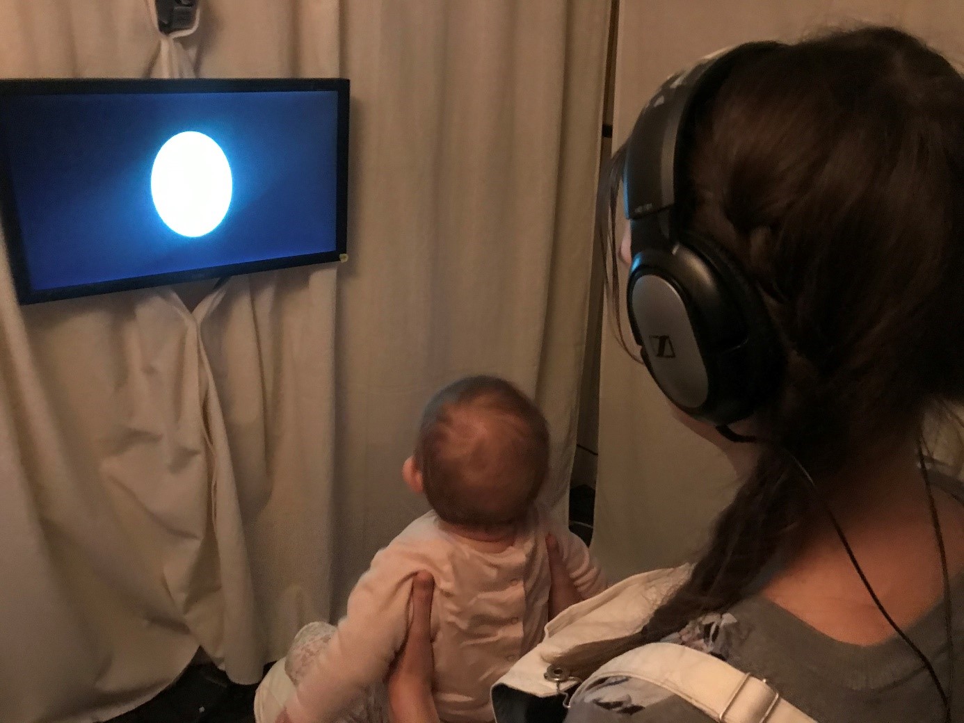 b&eacute;b&eacute; regardant un &eacute;cran, sur les genoux d'une accompagnatrice